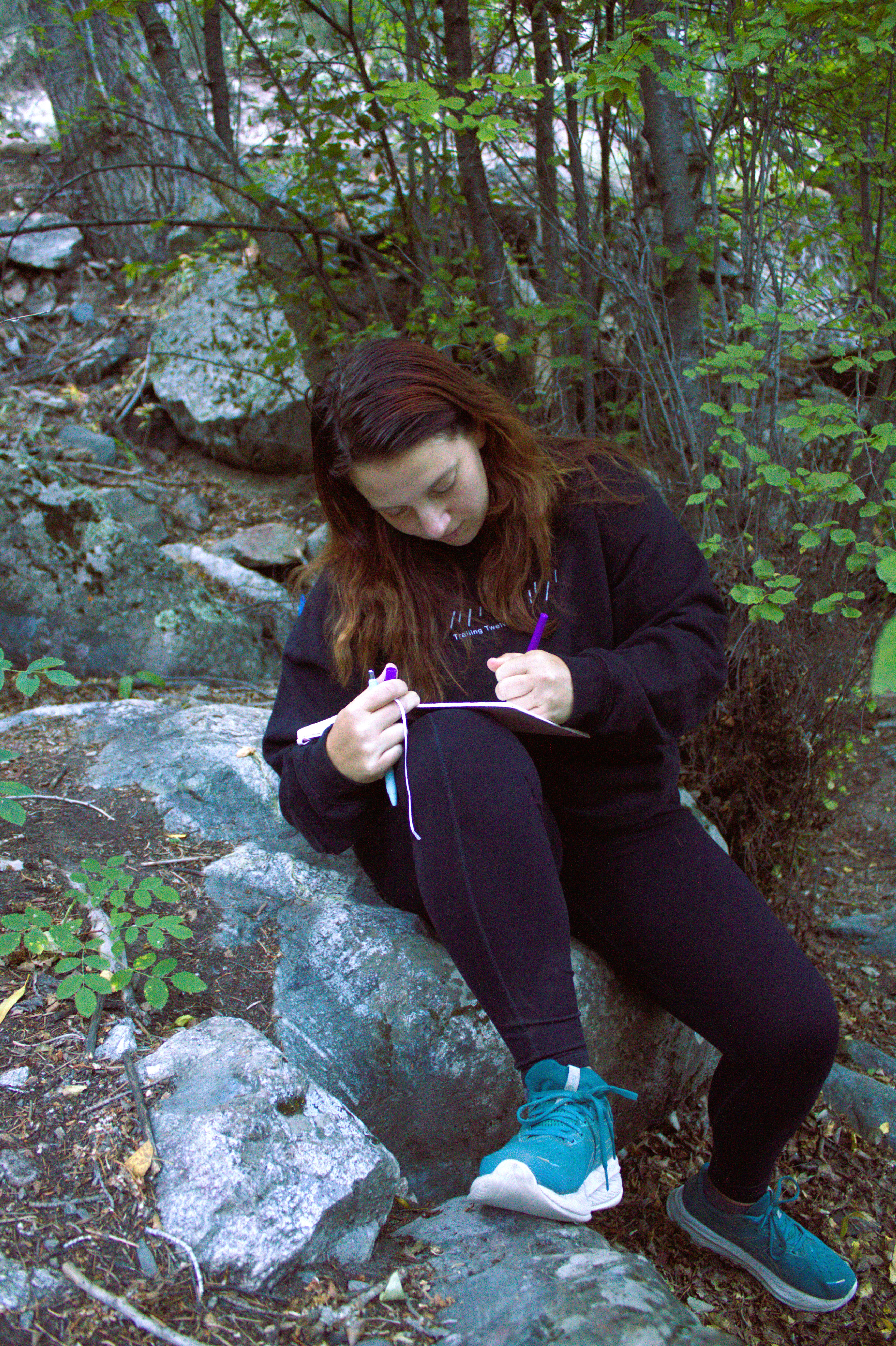 Justina writing outdoors on a rock